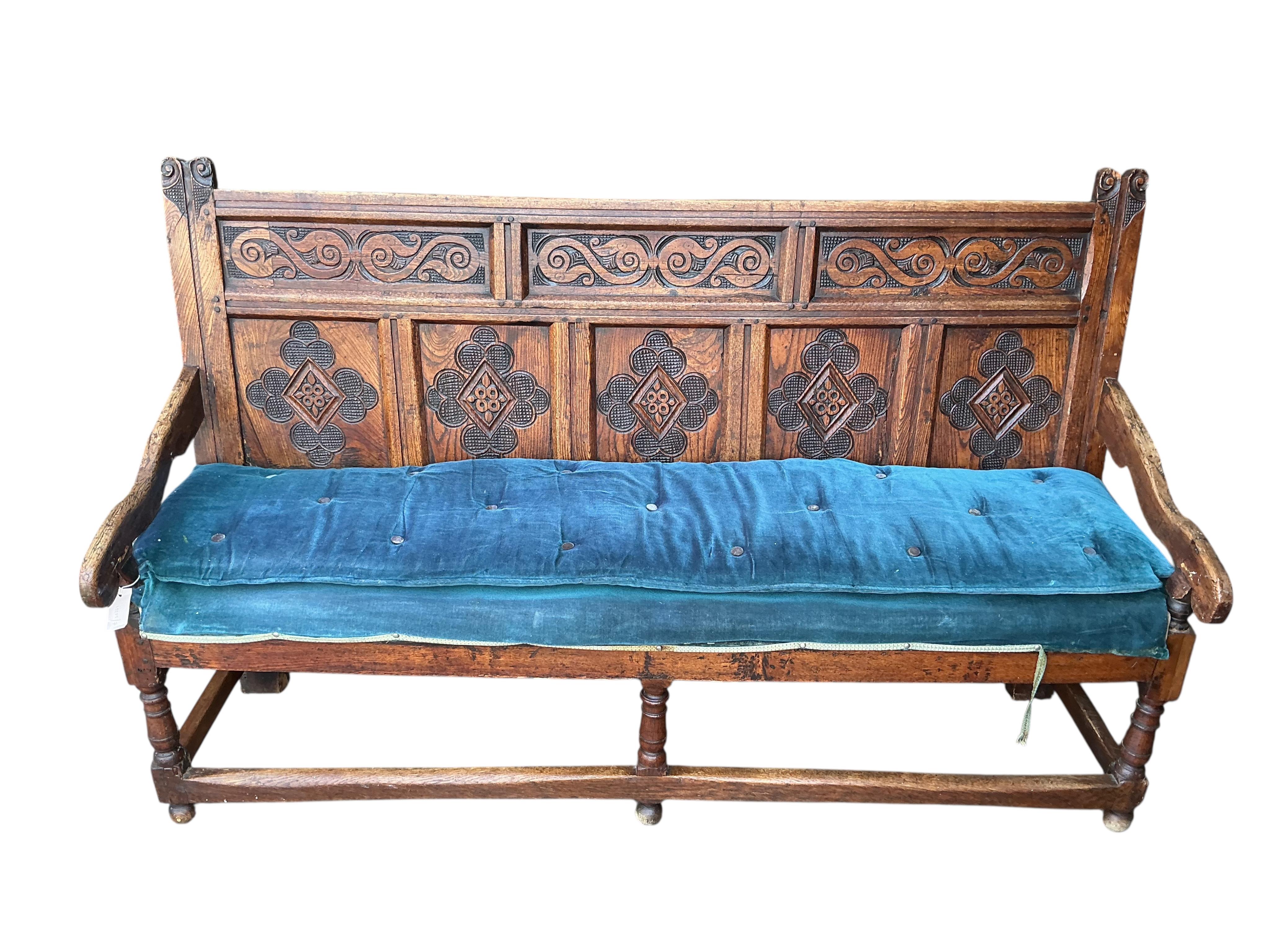 An 18th century panelled oak settle, later carved, width 177cm, depth 55cm, height 110cm